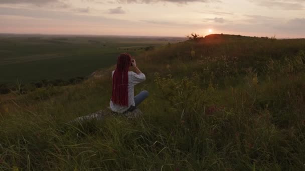 A lány ráül a kőre és elkezd lövöldözni a kamerájára. — Stock videók