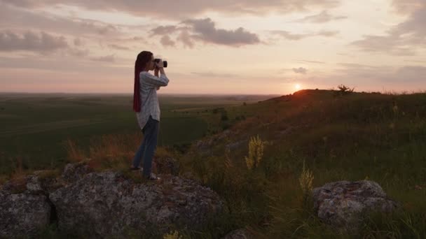 女孩站在大石头上，开始用相机拍摄 — 图库视频影像