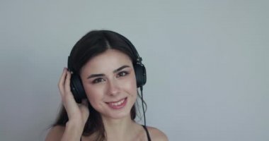 Gülümseyen kız müzik eşliğinde sallanıyor ve arka plandaki kameraya gözlerini kapıyor.