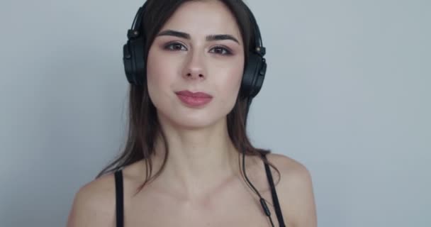 Mädchen mit Kopfhörer, Ohrenbecher anfassen, Kopf wippen, dann beginnt sie zu lächeln — Stockvideo