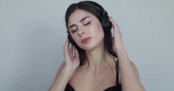 Дівчина в бюстгальтері з закритими очима вистрибує з музики на навушники і кусає губу — стокове відео