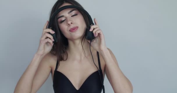 Dziewczyna zdejmuje słuchawki, umieszcza je nad uszami kamery i tańczy — Wideo stockowe