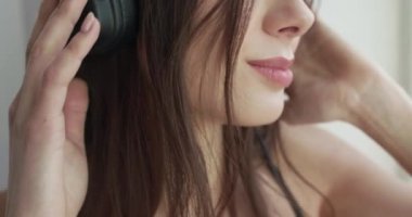 Kızın yakın portresi pencere eşiğinde rahatlıyor, müzik dinliyor, kameraya gülümsüyor.