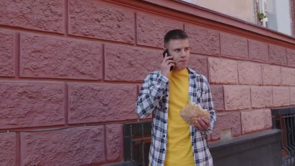 Personne parle au téléphone et mâcher un hamburger — Video