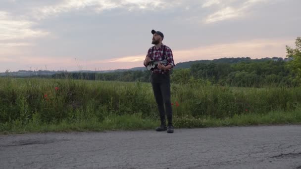 El hombre con estilo juega en la carretera en la pequeña guitarra — Vídeos de Stock