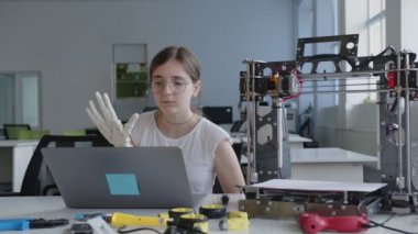 Liseli kız 3D baskılı el hakkında notlar yazıyor.