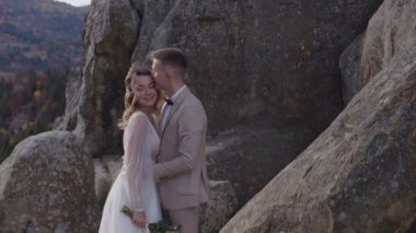 Mountain Rock 'ta bir düğün çifti. Mutlu yeni evlilerin birbirlerine aşık olmalarının ve dağın tepesinde dikilmelerinin görüntüsü..