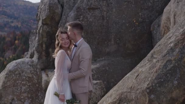 Pareja de bodas en Mountain Rock. Vista de los recién casados felices enamorados abrazándose y de pie en la cima de la montaña. — Vídeos de Stock