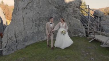 Dağlarda genç bir çift. Kayalıklarda yürüyen yeni evliler. Damat gelinin elini tutar..