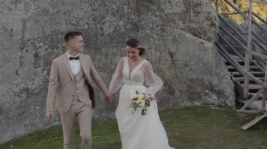 Dağlarda genç bir çift. Kayalıklarda yürüyen yeni evliler. Damat gelinin elini tutar..
