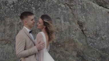 Dağlarda genç bir çift. Yeni evliler kayalıklarda sarılıyorlar..