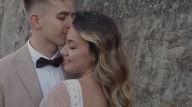 Dağlarda genç bir çifte yakın durun. Yeni evliler kayalıklarda sarılıyorlar..