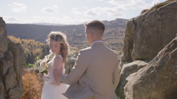 Vista majestosa da montanha rochosa e belos recém-casados que se aproximam um do outro. — Vídeo de Stock