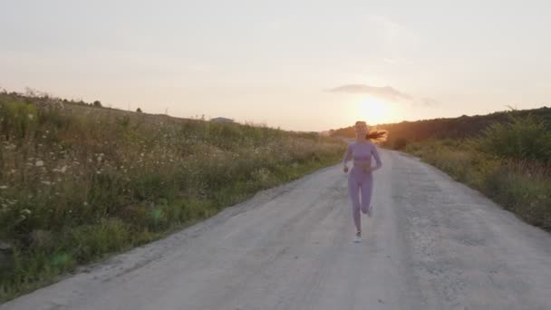 Widok z przodu biegnącej dziewczyny na wieczorny runset — Wideo stockowe
