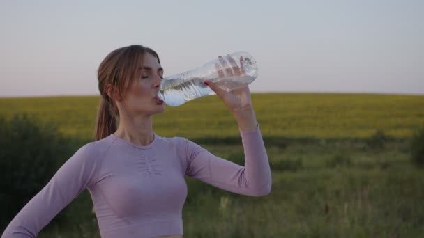 Mädchen steht und trinkt Wasser unter freiem Himmel — Stockvideo