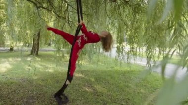 Kız havadaki ipeğin üzerinde duruyor ve bacağını kaldırıyor.