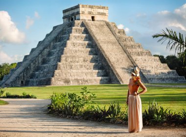 Meksika 'nın Chichen Itza şehrinde Kukulcan piramidinin arka planında duran şapkalı kız turist. Seyahat kavramı. Yucatan, Meksika 'da Maya piramitleri.
