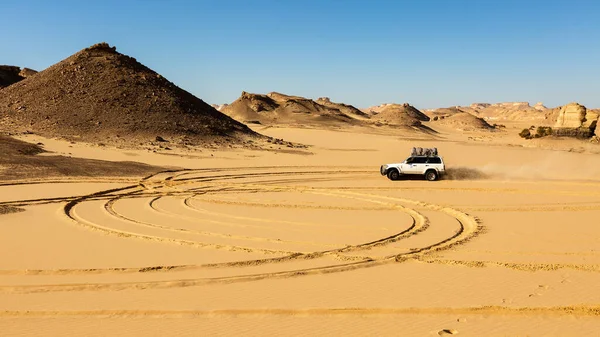 Off-road vehicle drives through the sand of a black and white desert .Egypt