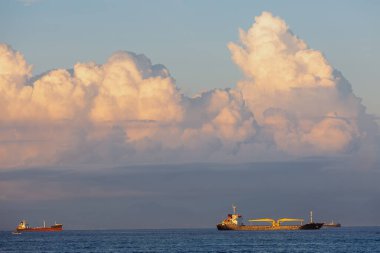 Gökyüzünün arka planında büyük beyaz bulutlu gemiler gün batımında.