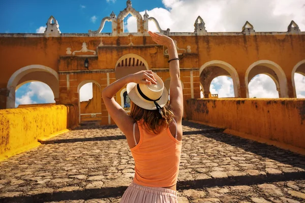 Girl tourist in a hat in the yellow Mexican city of Izamal, Mexico