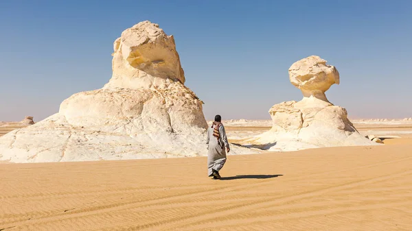 An Egyptian walks near sandstone formations in the Black and White Desert. Egypt.