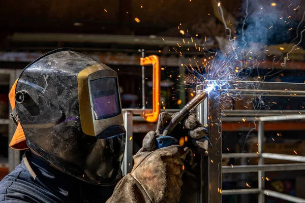 Worker with protective mask welding metal cage in kibbutz ravid, israel. cooperative work in modern socialist lifestyle. smoke.