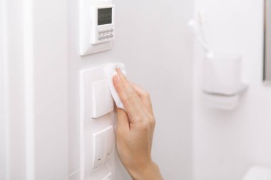Temizlik düğmeleri ve prizleri mikrofiber bezle temizliyorum. Kadın eli temizlik için ıslak mendil kullanıyor. Hastane ve halka açık alanlarda korona virüsüne karşı yüzeylerin sterilize edilmesi