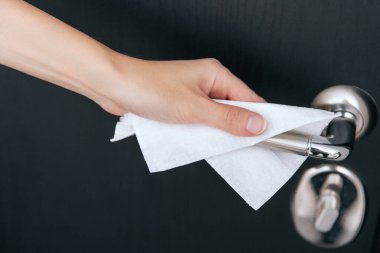 Siyah kapı kollarını antiseptik ıslak mendille temizliyorum. Ev kapısı bağlantısını temizlemek için havlu kullanan kadın eli. Hastane ve halka açık alanlarda korona virüsüne karşı yüzeylerin sterilize edilmesi