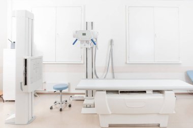 Modern hastanenin röntgen bölümü. Boş yataklı tarama makineli radyoloji odası. Teknisyen röntgen cihazını ayarlıyor. Modern klinikte göğüs, kalp ve akciğerler taranıyor.
