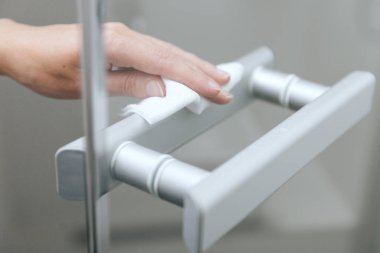 Cam kapı kollarını antiseptik ıslak mendille temizliyorum. Ev kapısı bağlantısını temizlemek için havlu kullanan kadın eli. Hastane ve halka açık alanlarda korona virüsüne karşı yüzeylerin sterilize edilmesi