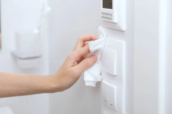 Interruptores de limpieza y enchufes con un paño de microfibra. Mujer mano usando toallita húmeda para limpiar el enlace de la puerta de la habitación. Desinfectar las superficies de prevención en los espacios hospitalarios y públicos contra el virus corona —  Fotos de Stock