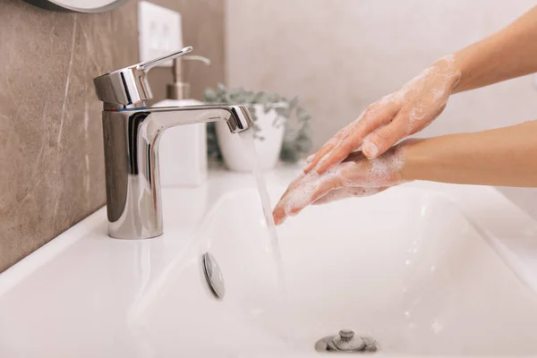 Washing hands under the flowing water tap. Washing hands rubbing with soap for corona virus prevention, hygiene to stop spreading corona virus in or public wash room. Hygiene concept hand detail