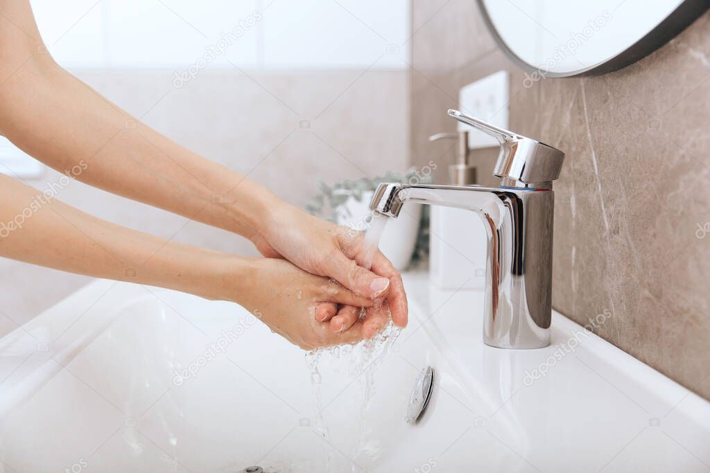 Washing hands under the flowing water tap. Washing hands rubbing with soap for corona virus prevention, hygiene to stop spreading corona virus in or public wash room. Hygiene concept hand detail
