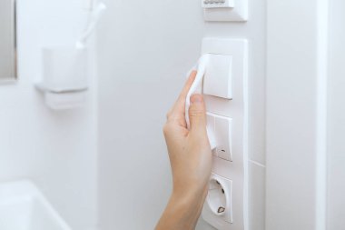 Temizlik düğmeleri ve prizleri mikrofiber bezle temizliyorum. Kadın eli temizlik için ıslak mendil kullanıyor. Hastane ve halka açık alanlarda korona virüsüne karşı yüzeylerin sterilize edilmesi