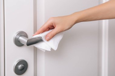 Antiseptik ıslak mendil ve eldivenle kapı kolları temizleniyor. Hastane ve kamusal alanlarda korona virüsüne karşı korunma yüzeylerini sterilize edin. Kadın eli temizlik için havlu kullanıyor.