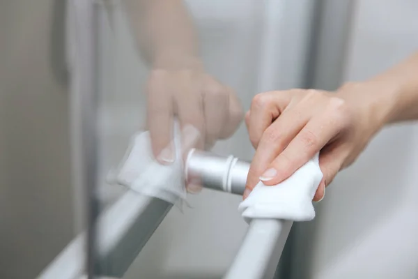 Rengöring glasdörr handtag med en antiseptisk våt torka. Kvinna hand med hjälp av handduk för rengöring hem rum dörr länk. Sanitisera ytor förebyggande på sjukhus och offentliga utrymmen mot koronavirus — Stockfoto