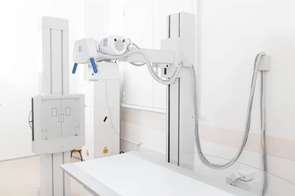Röntgenabteilung in einem modernen Krankenhaus. Radiologie-Raum mit Scanner mit leerem Bett. Techniker justieren ein Röntgengerät. Brust, Herz und Lungen in moderner Klinik-Praxis abtasten — Stockfoto