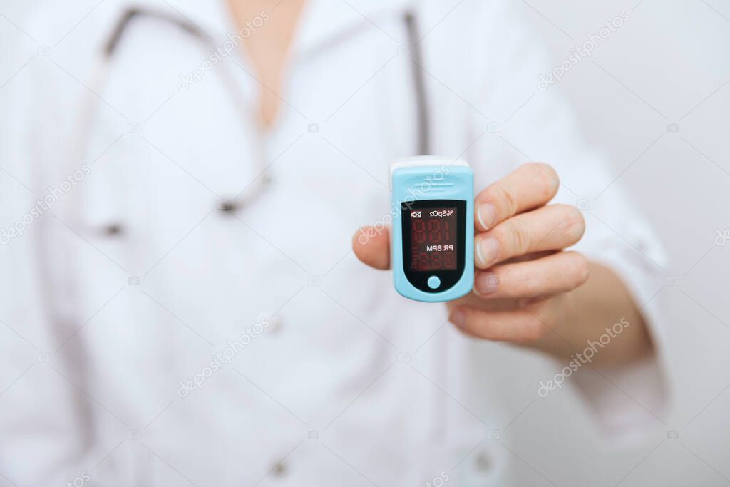 Pulse oximeter with hand of doctor isolated on white. The concept of portable digital device to measure persons oxygen saturation. Measuring oxygen saturation, pulse rate and oxygen levels.