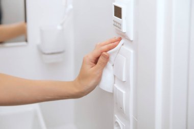 Temizlik düğmeleri ve prizleri mikrofiber bezle temizliyorum. Kadın eli temizlik için ıslak mendil kullanıyor. Hastane ve halka açık alanlarda korona virüsüne karşı yüzeylerin sterilize edilmesi