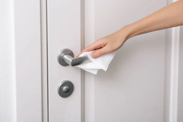 消毒用のぬれたワイプと手袋でドアのハンドルを掃除します。病院や公共スペースでコロナウイルスに対する表面の予防を衛生化します。家のドアのリンクを掃除するためにタオルを使用して女性の手 — ストック写真