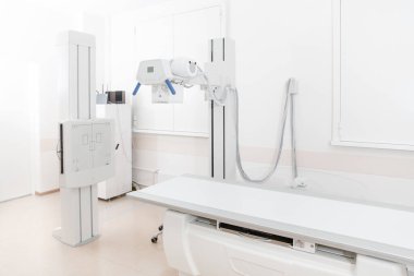 Modern hastanenin röntgen bölümü. Boş yataklı tarama makineli radyoloji odası. Teknisyen röntgen cihazını ayarlıyor. Modern klinikte göğüs, kalp ve akciğerler taranıyor.