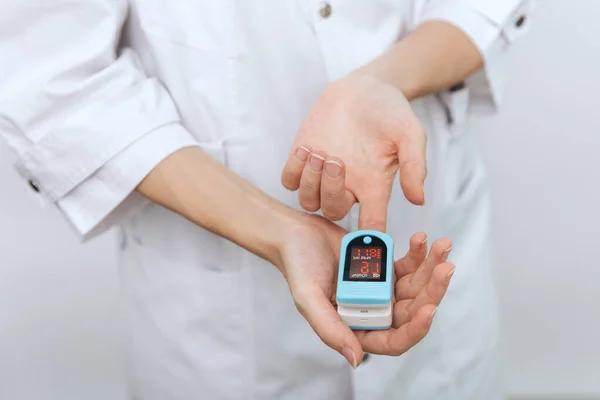 Pulsoximeter med hand av läkare isolerad på vitt. Begreppet bärbar digital anordning för att mäta personer syremättnad. Mätning av syremättnad, puls och syrehalt — Stockfoto