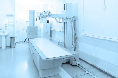 Modern hastanenin röntgen bölümü. Boş yataklı tarama makineli radyoloji odası. Teknisyen röntgen cihazını ayarlıyor. Modern klinikte göğüs, kalp ve akciğerler taranıyor.