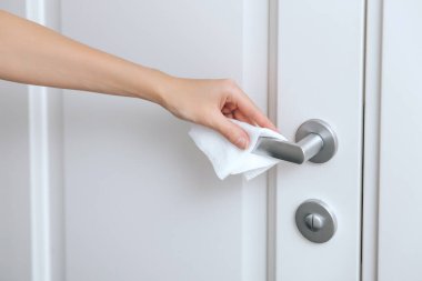 Antiseptik ıslak mendil ve eldivenle kapı kolları temizleniyor. Hastane ve kamusal alanlarda korona virüsüne karşı korunma yüzeylerini sterilize edin. Kadın eli temizlik için havlu kullanıyor.