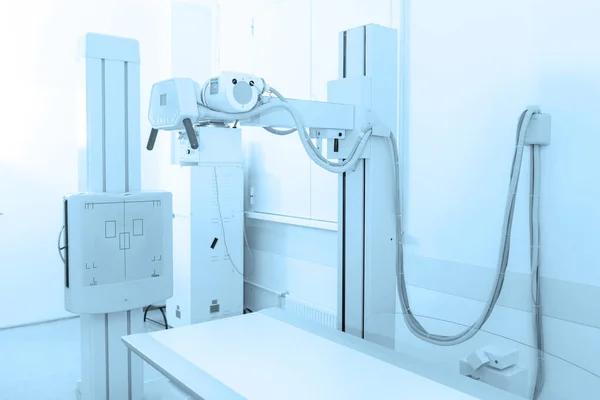 현대 병원 의 X- 레이 부서입니다. 방사선과에 빈 침대가 있는 스캔 기계가 있어요. 기술자가 엑스레이 기계를 조정하고 있어. 현대 진료소에서 가슴, 심장, 폐를 찍는 모습 — 스톡 사진