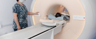 Tomografi tomografisi ya da hastanede MRI taraması olan doktor, hemşire ve hasta. Radyografi bölümünün içi. Beyaz odada teknolojik olarak gelişmiş ekipmanlar var. Manyetik rezonans tanılama makinesi