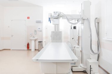Modern hastanenin röntgen bölümü. Boş yataklı tarama makineli radyoloji odası. Teknisyen röntgen cihazını ayarlıyor. Modern klinikte göğüs, kalp ve akciğerler taranıyor.