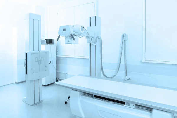 Rentgenové oddělení v moderní nemocnici. Radiologická místnost se skenerem s prázdnou postelí. Technik nastavuje rentgen přístroje. Skenování hrudníku, srdce, plic v moderní klinice — Stock fotografie