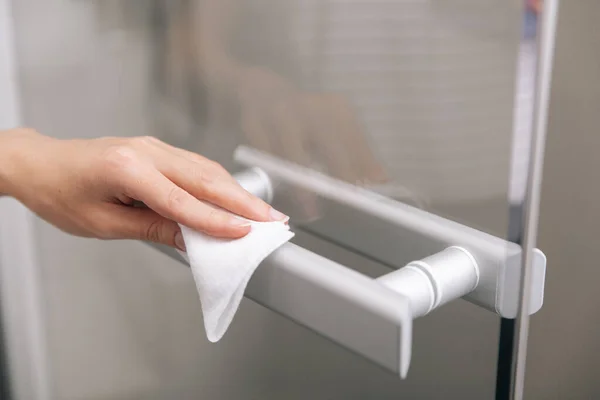 Cleaning glass door handles with an antiseptic wet wipe. Woman hand using towel for cleaning home room door link. Sanitize surfaces prevention in hospital and public spaces against corona virus — Stock Photo, Image