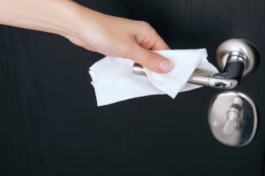 Siyah kapı kollarını antiseptik ıslak mendille temizliyorum. Hastane ve kamusal alanlarda korona virüsüne karşı korunma yüzeylerini sterilize edin. Kadın eli temizlik için havlu kullanıyor.